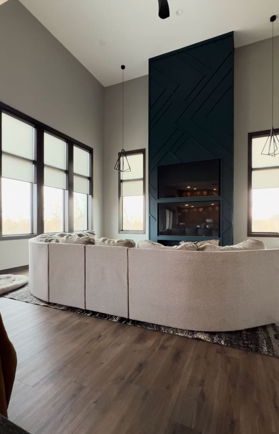 Roller Shades on tall windows in a great room with a black fireplace