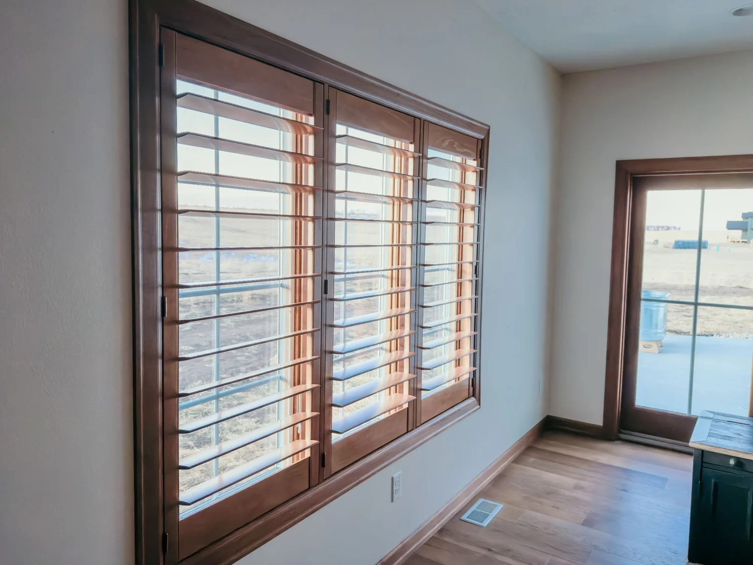 Wood shutters on a sliding glass door, installed by 605 Blinds